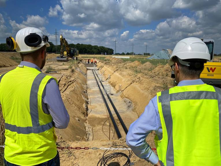 Zwei Arbeiter sehen in einen Graben hinunter